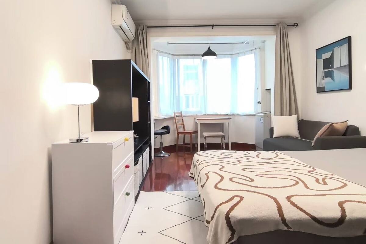 A compact hotel room with a bed, a desk, a chair, a television, and a wardrobe.