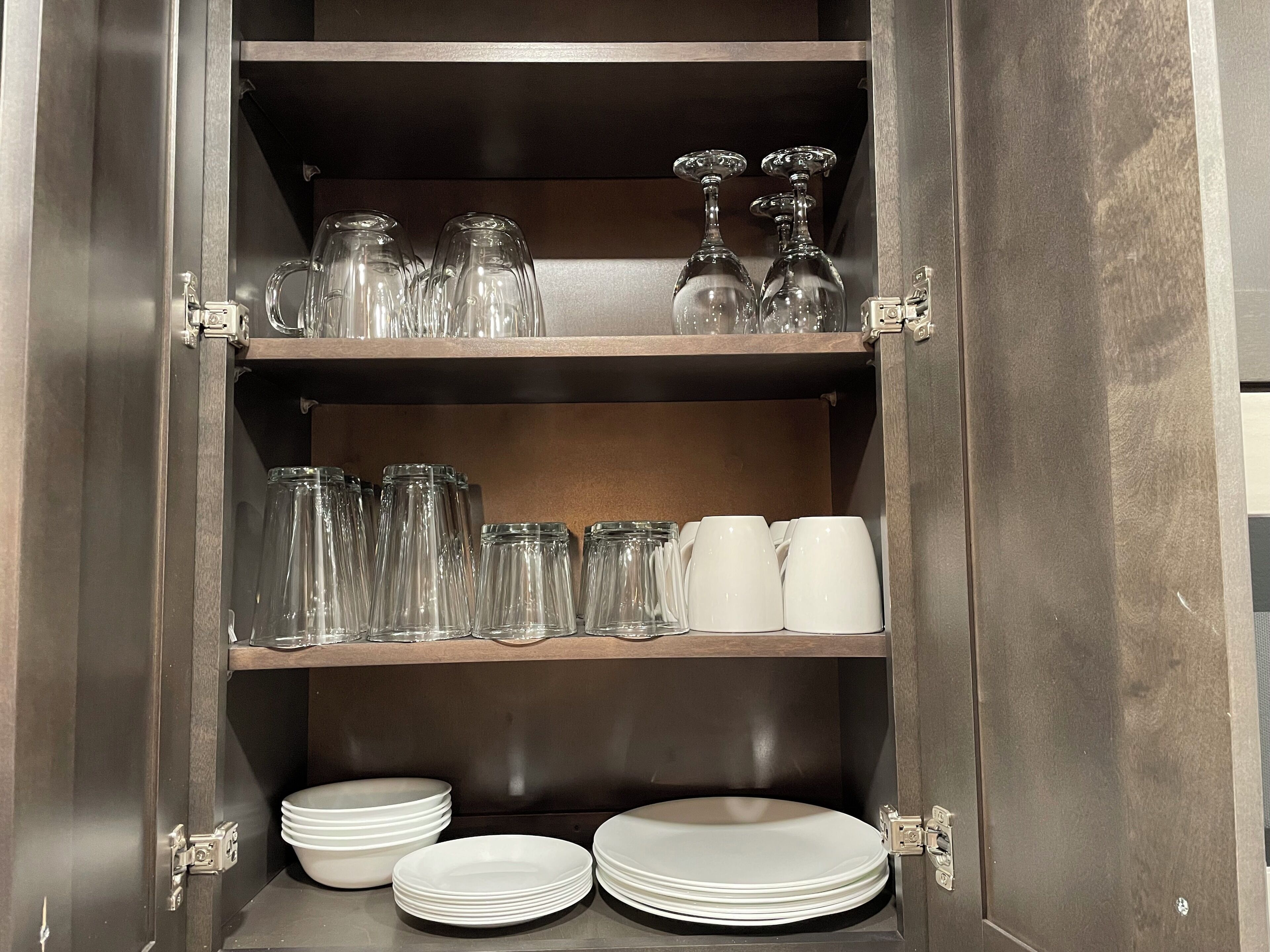A cabinet with shelves holding glassware and plates.