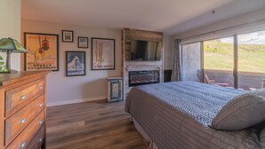 Una camera da letto con un letto grande, un comò in legno, un camino e vista sull'esterno.