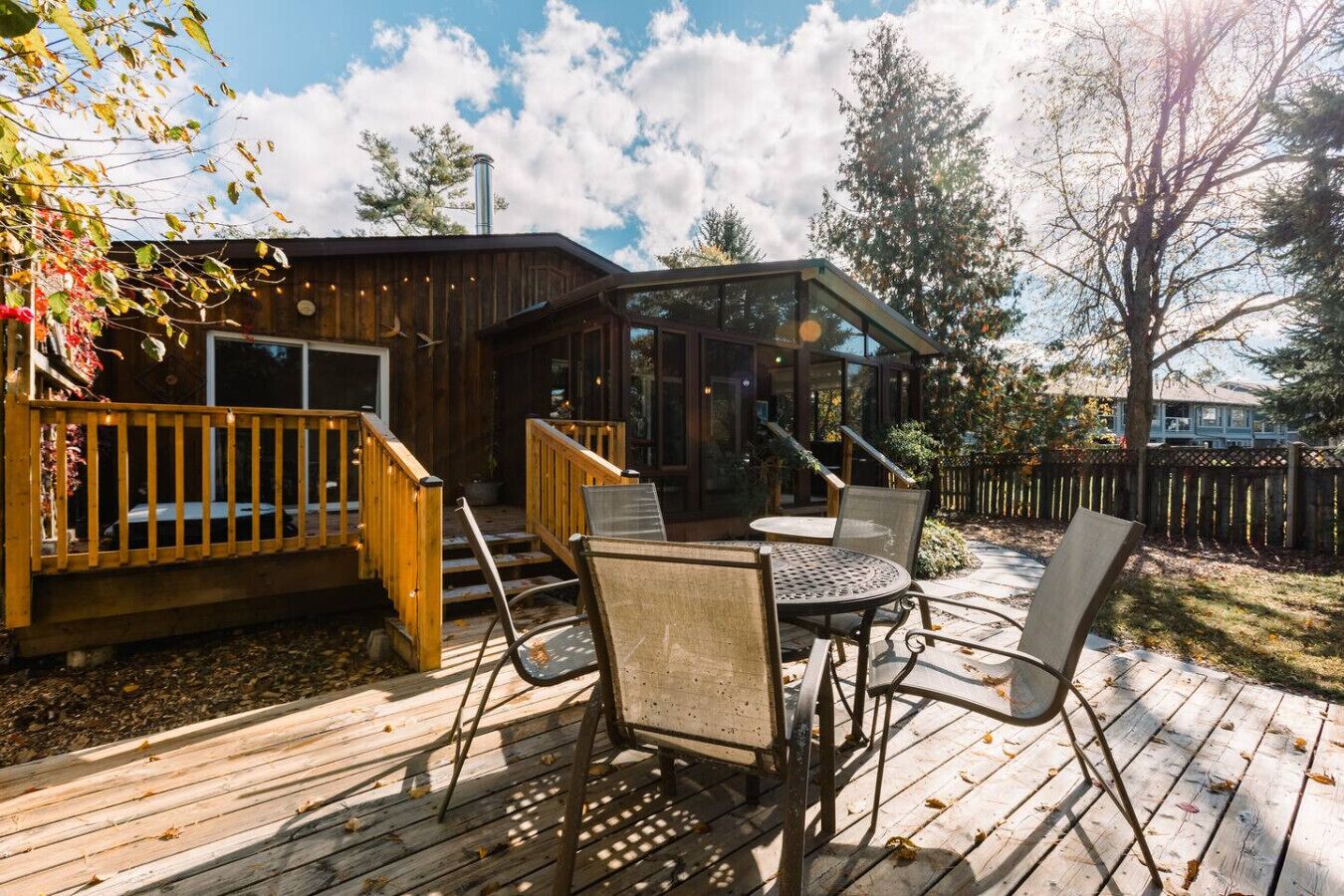 A wooden deck with outdoor seating and a glass-enclosed structure.