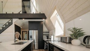 Una cocina moderna con una isla central, electrodomésticos de acero inoxidable y vistas al piso superior.
