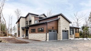 Una moderna casa a due piani con facciata in pietra, ampie finestre e un garage.