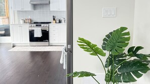 Una cocina moderna con armarios blancos, electrodomésticos de acero inoxidable y un ventanal grande.