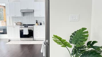 A modern kitchen with white cabinets, stainless steel appliances, and a large window.