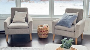 Una sala de estar con dos sillones, una cesta tejida y una mesa de centro con una planta.