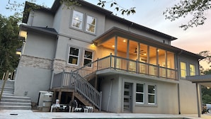 Una casa de dos pisos con balcón, una escalera y zona de piscina.