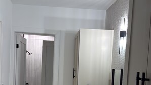 Un baño moderno con un espejo grande, encimera de mármol blanco y muebles de color beige.