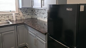 A kitchen with grey cabinets, a black refrigerator, and a tiled backsplash. - Family & Pet Friendly 1-BD Apt mins from Downtown, UH, Med Center & Attractions (Houston)