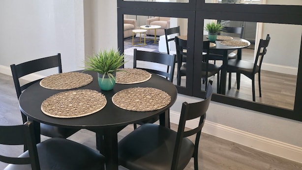 A dining area with a round table, black chairs, and woven placemats. There are potted plants on the table. - Family & Pet Friendly 1-BD Apt mins from Downtown, UH, Med Center & Attractions (Houston)