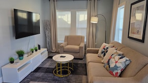 A modern living room with a flat-screen TV, a sofa, a coffee table, and a floor lamp. - Family & Pet Friendly 1-BD Apt mins from Downtown, UH, Med Center & Attractions (Houston)