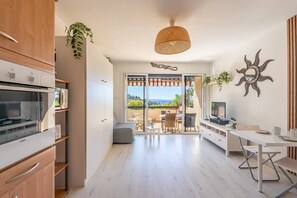 A modern kitchen with a built-in oven, a dining area with a table and chairs, and a large sliding glass door leading to an outdoor patio. - L'appartement Cala Nova (BORMES LES MIMOSAS)