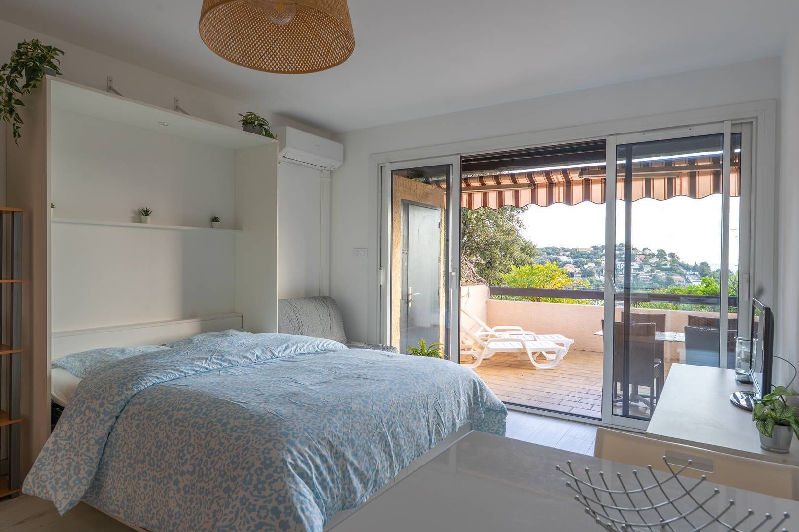 Un dormitorio con cama, una silla, una mesa y un balcón con vistas.