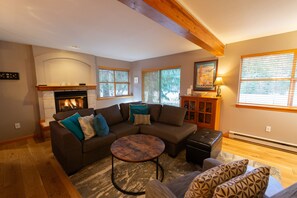 A living room with a fireplace, a sectional sofa, a round coffee table, and a patterned rug. - Comfortable two-bedroom town home with room for the whole family (Whistler)