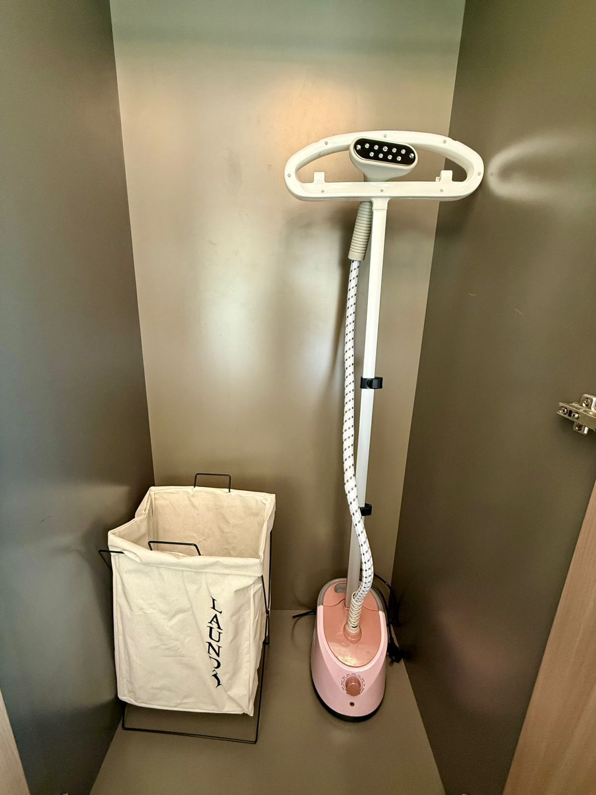 A compact room with a standing vacuum cleaner, a white storage bag, and a door.
