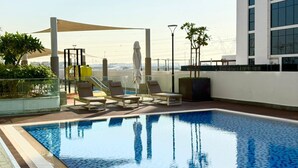 Ein Pool auf dem Dach mit Liegestühlen und Blick auf die Stadtlandschaft.
