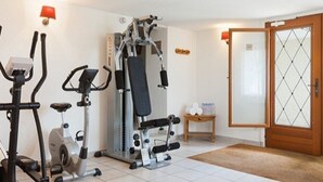 A home gym with exercise equipment, a door, and a small table with items on it. - T2 with breathtaking view of Lake Geneva (Lugrin)
