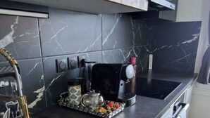 A kitchen with wooden cabinets, a black countertop, a sink, and a dishwasher. - T2 with breathtaking view of Lake Geneva (Lugrin)