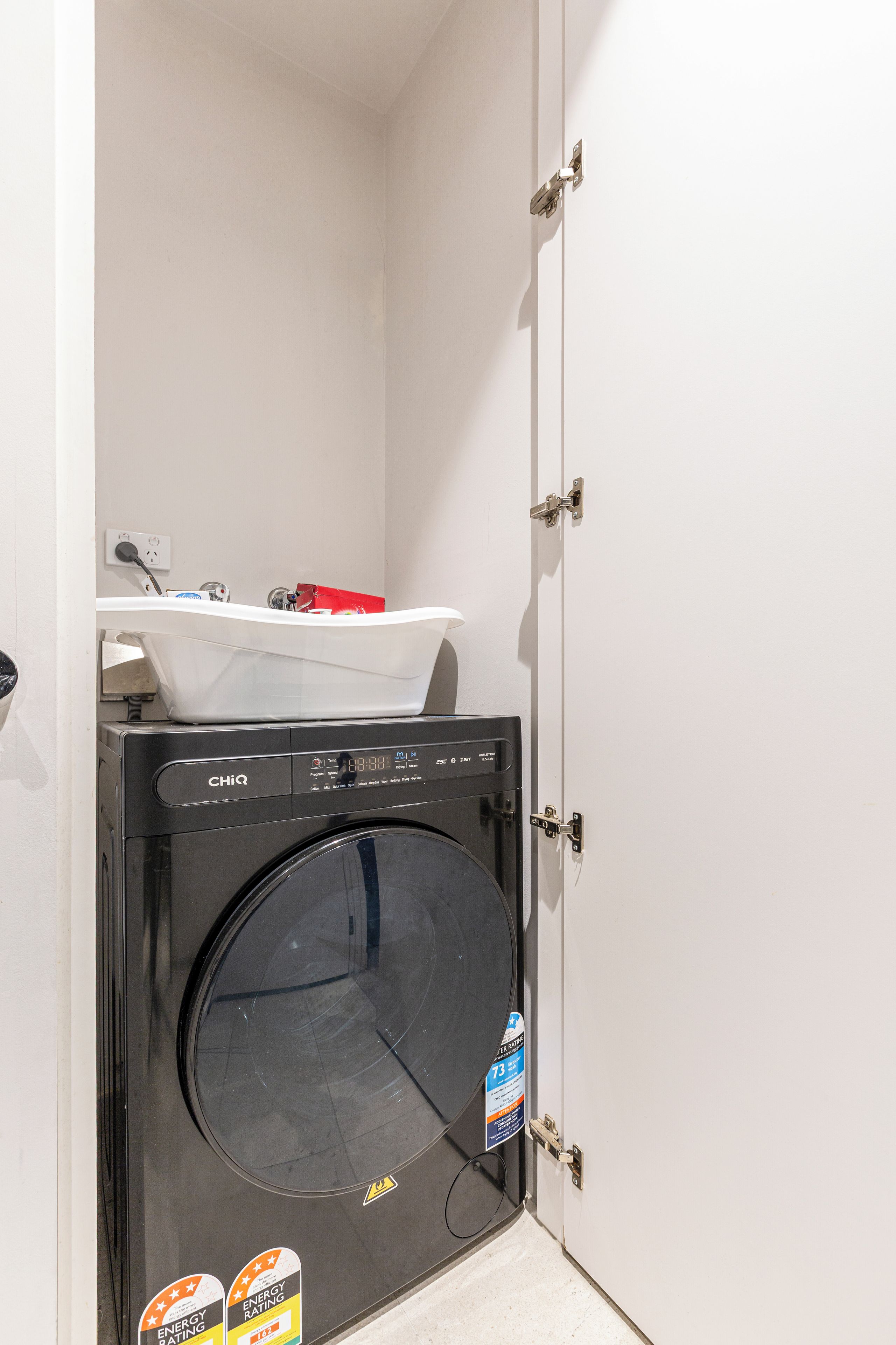 A compact laundry room with a washing machine and a sink.