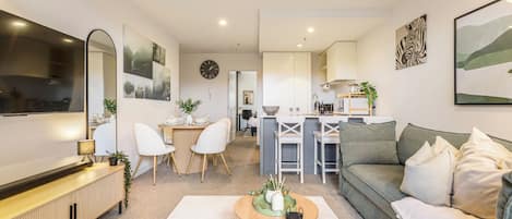 A modern living room with a sofa, a coffee table, and a dining area with chairs and a table.