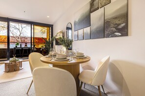 A dining area with a round table set for four, surrounded by chairs. There are framed artworks on the wall above the table. - Urban Oasis | Sleep 6 | Free Parking | Nintendo Switch (Collingwood)