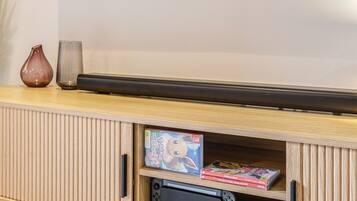 A flat-screen TV mounted on a wall above a wooden entertainment unit with a gaming console and video games.