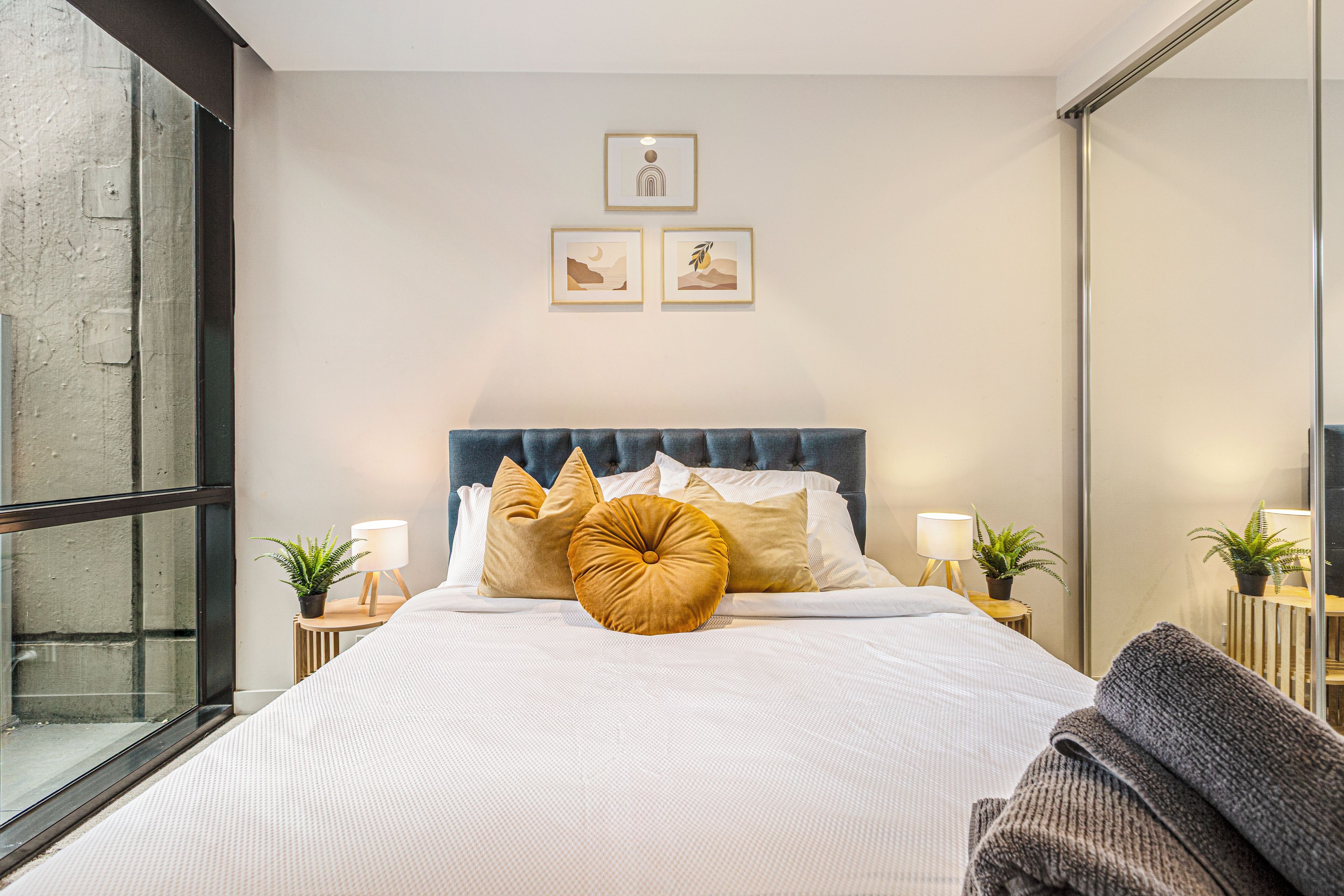 A modern bedroom with a large bed, a tufted headboard, and bedside tables with lamps.
