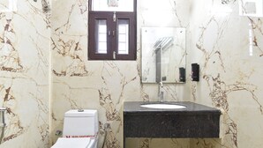 A bathroom with a toilet, sink, and mirror. - Hotel D7 (Jaipur)