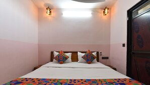 A room with a bed, two wall-mounted lights, a door with a lock, and a patterned bedspread. - Hotel D7 (Jaipur)