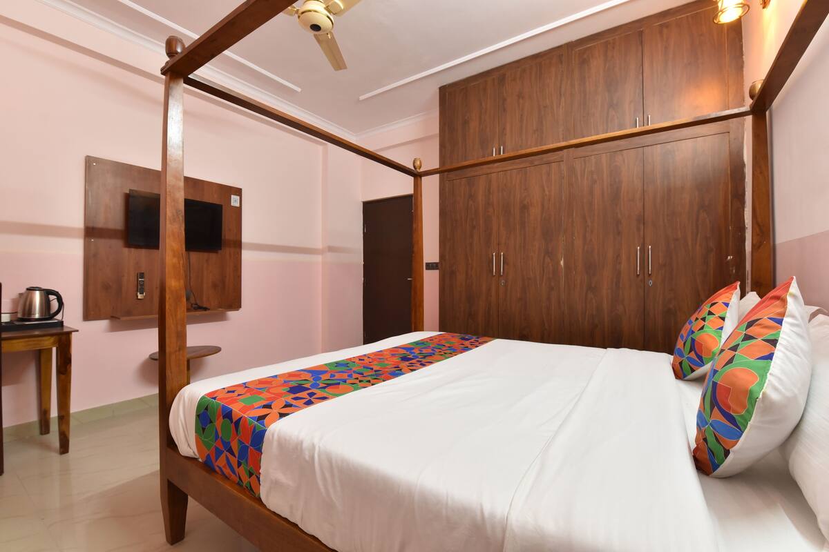 Quarto com cama de dossel, guarda-roupa de madeira e uma pequena mesa com chaleira.