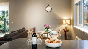 A dining area with a table set for two, a bowl of fruit, and a bottle of wine. - 2 bedroom accommodation in Tarves (Tarves)