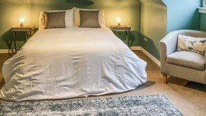 A bedroom with a large bed, two bedside tables with lamps, a chair, and a window. - 2 bedroom accommodation in Tarves (Tarves)