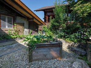Ein rustikales Holzhaus mit einem Vorgarten, der ein erhöhter Blumenkasten und verschiedene Pflanzen umfasst.