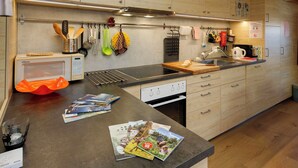 Een moderne keuken met houten kastjes, een ingebouwde magnetron en een roestvrijstalen spoelbak.