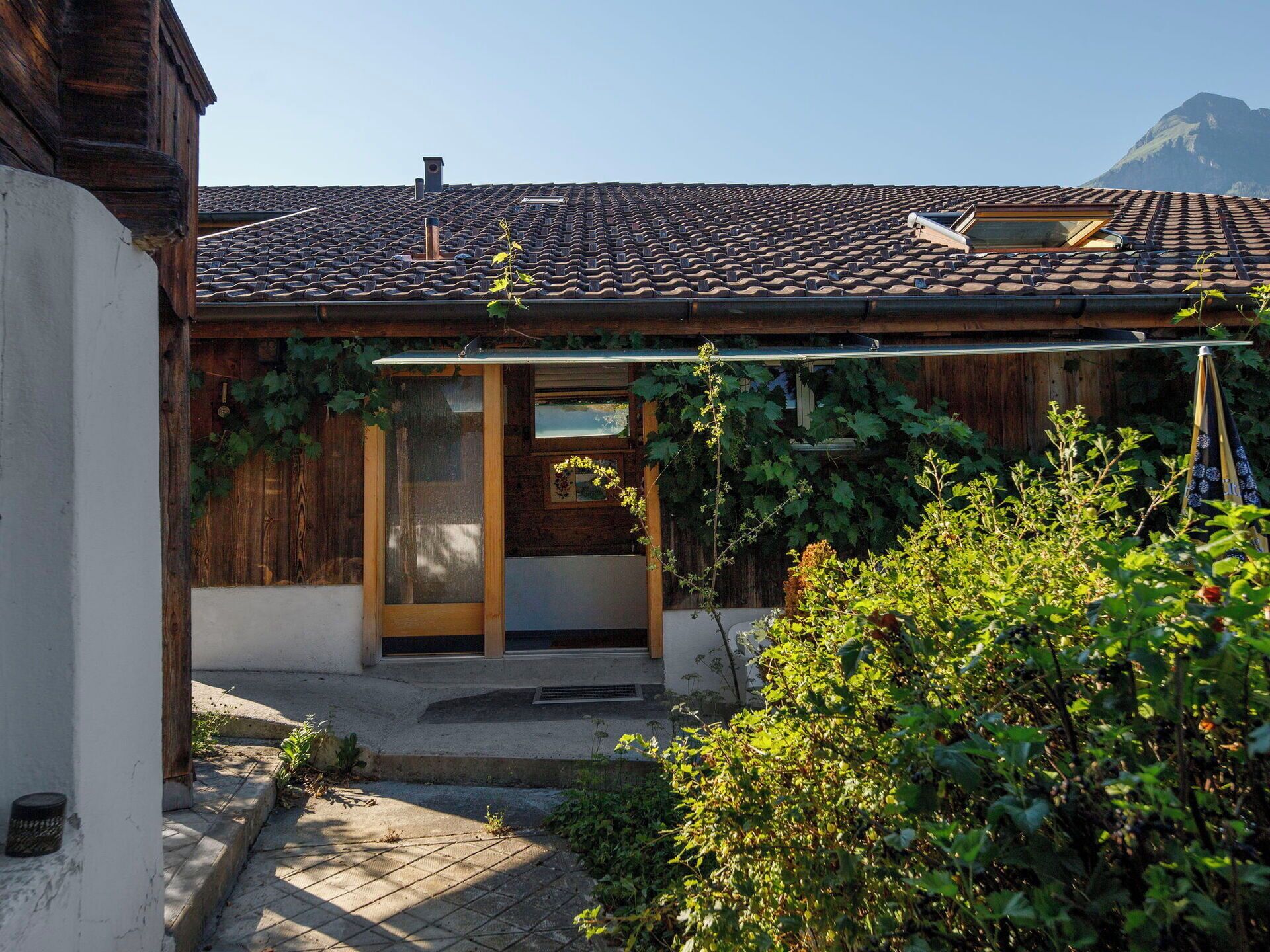 A traditional wooden house with a tiled roof, a wooden door, and a small porch area.