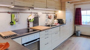 Een moderne keuken met houten kastjes, een ingebouwde kookplaat en een aanrecht met verschillende keukengerei.