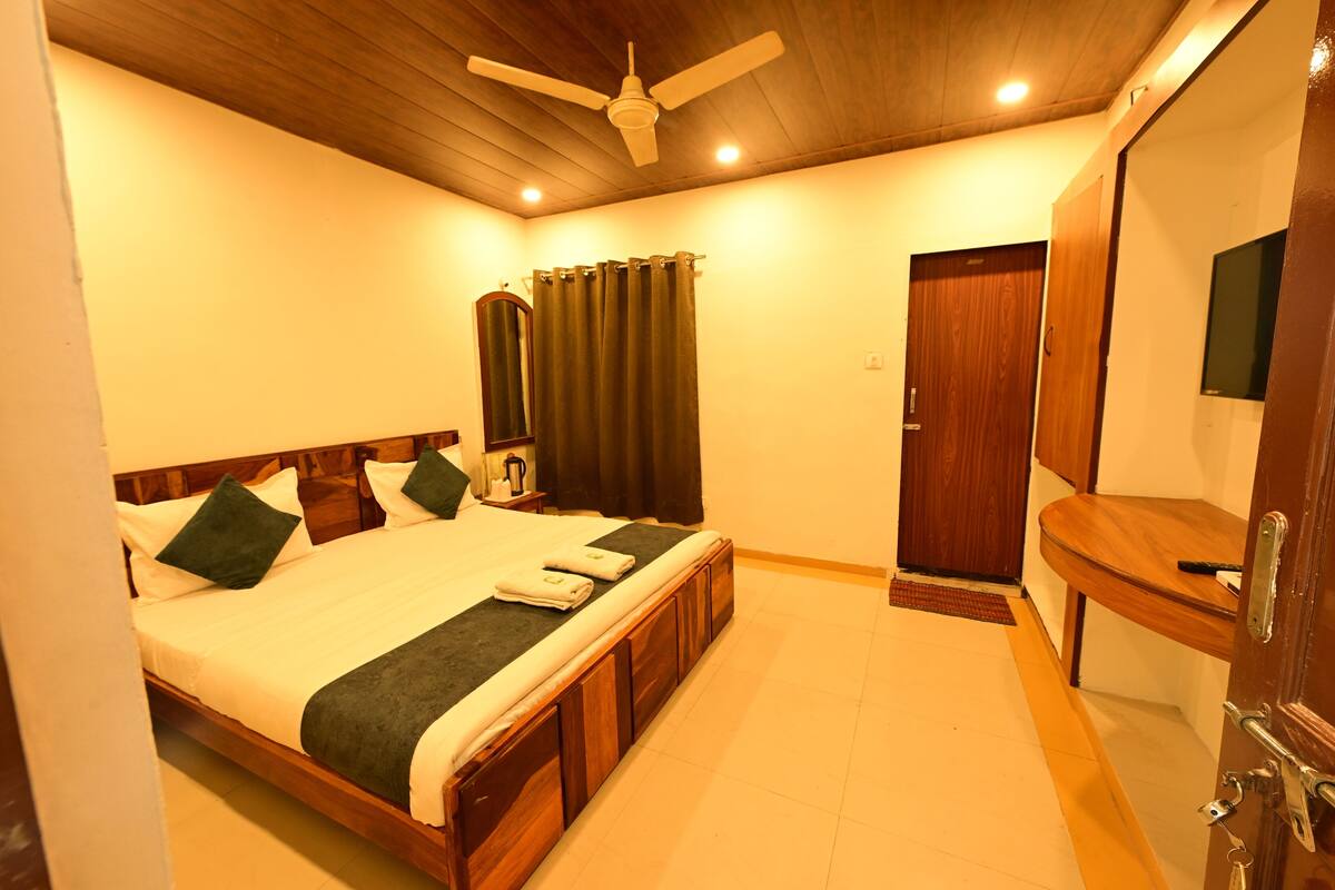 A bedroom with a wooden bed, a ceiling fan, a mirror, and a wooden door.