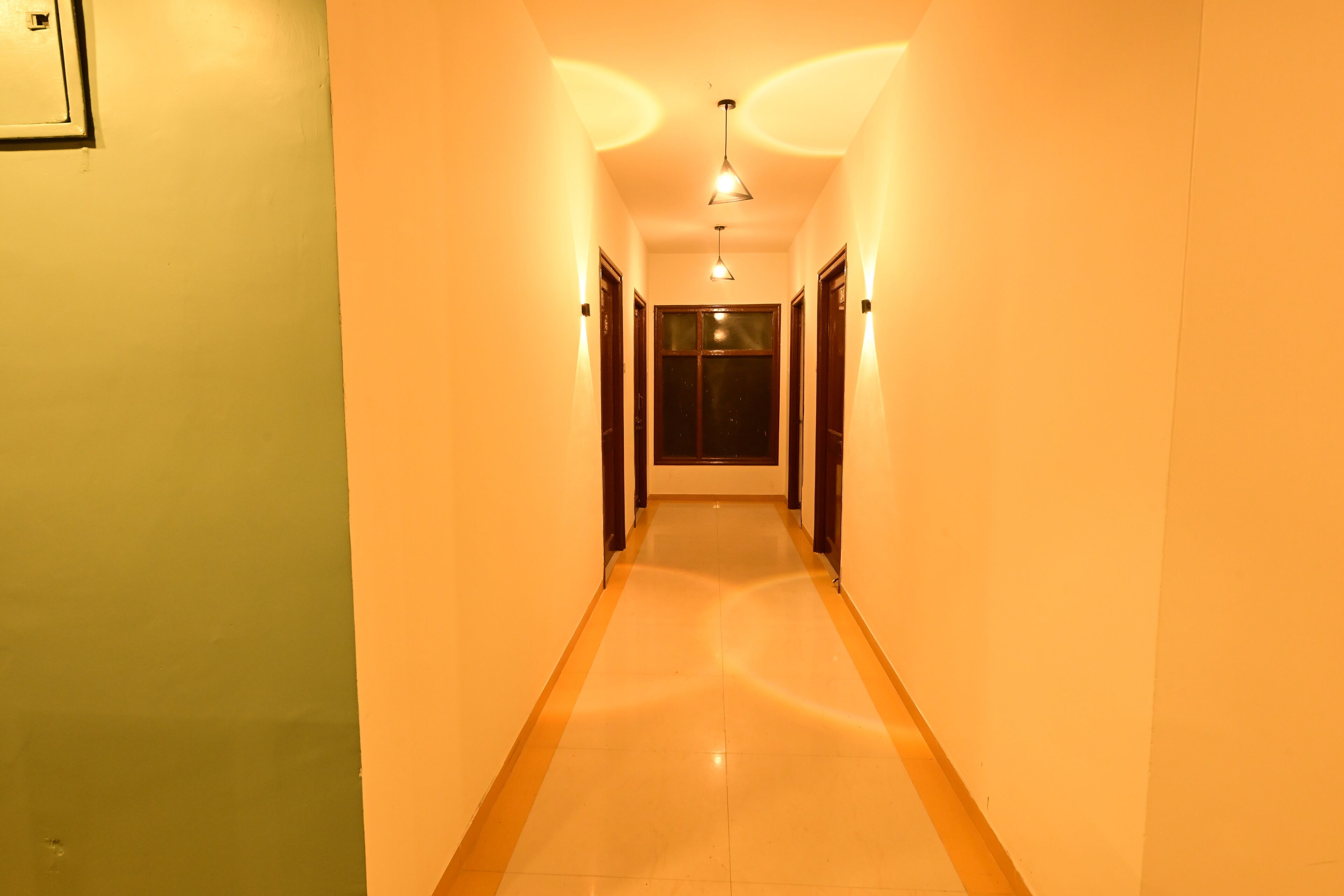 A hallway with a light-colored floor and walls, leading to a door at the end.