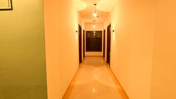 A hallway with a light-colored floor and walls, leading to a door at the end.