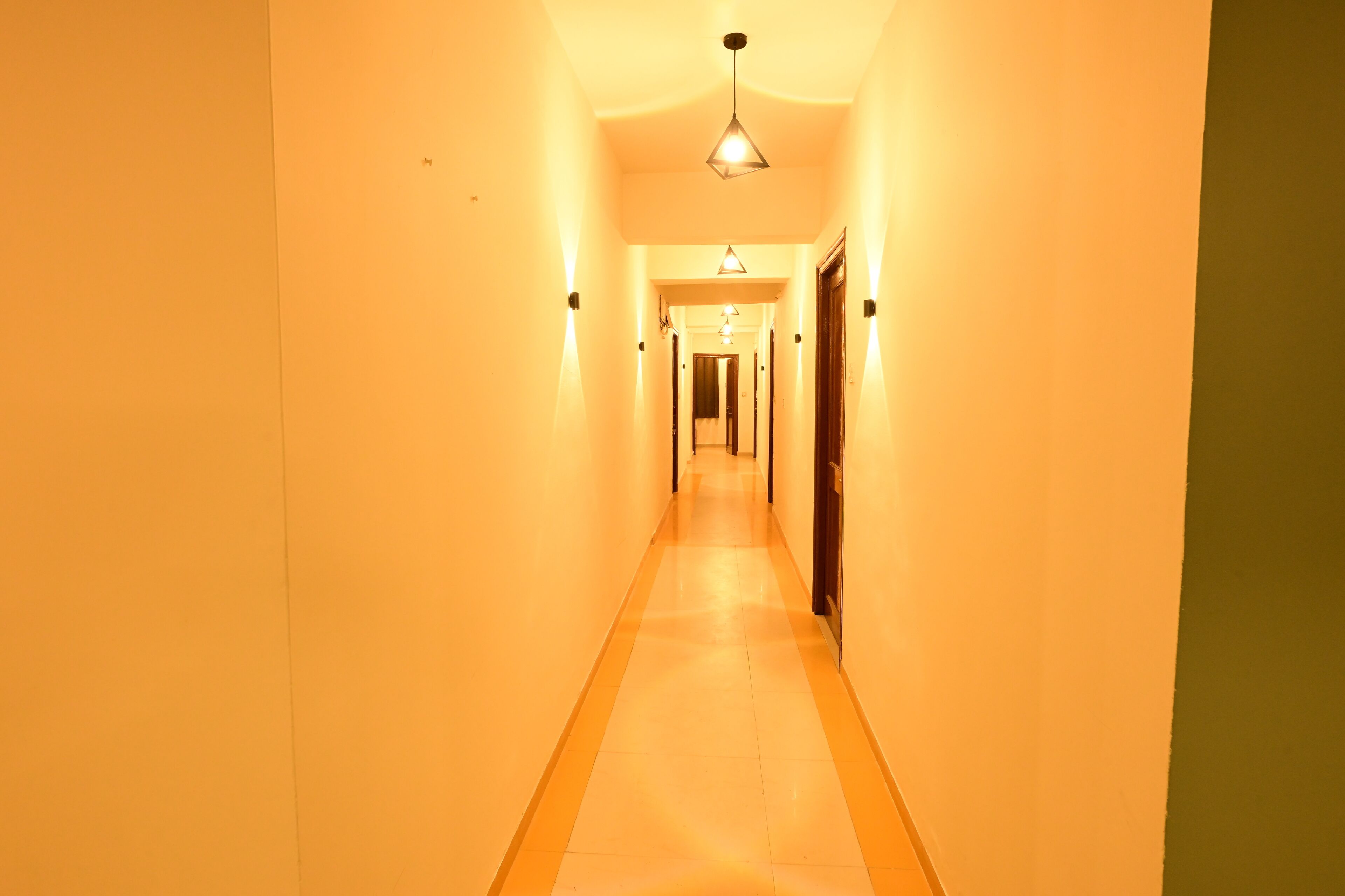 A long, narrow hallway with a light-colored floor and walls, leading to a door at the end.