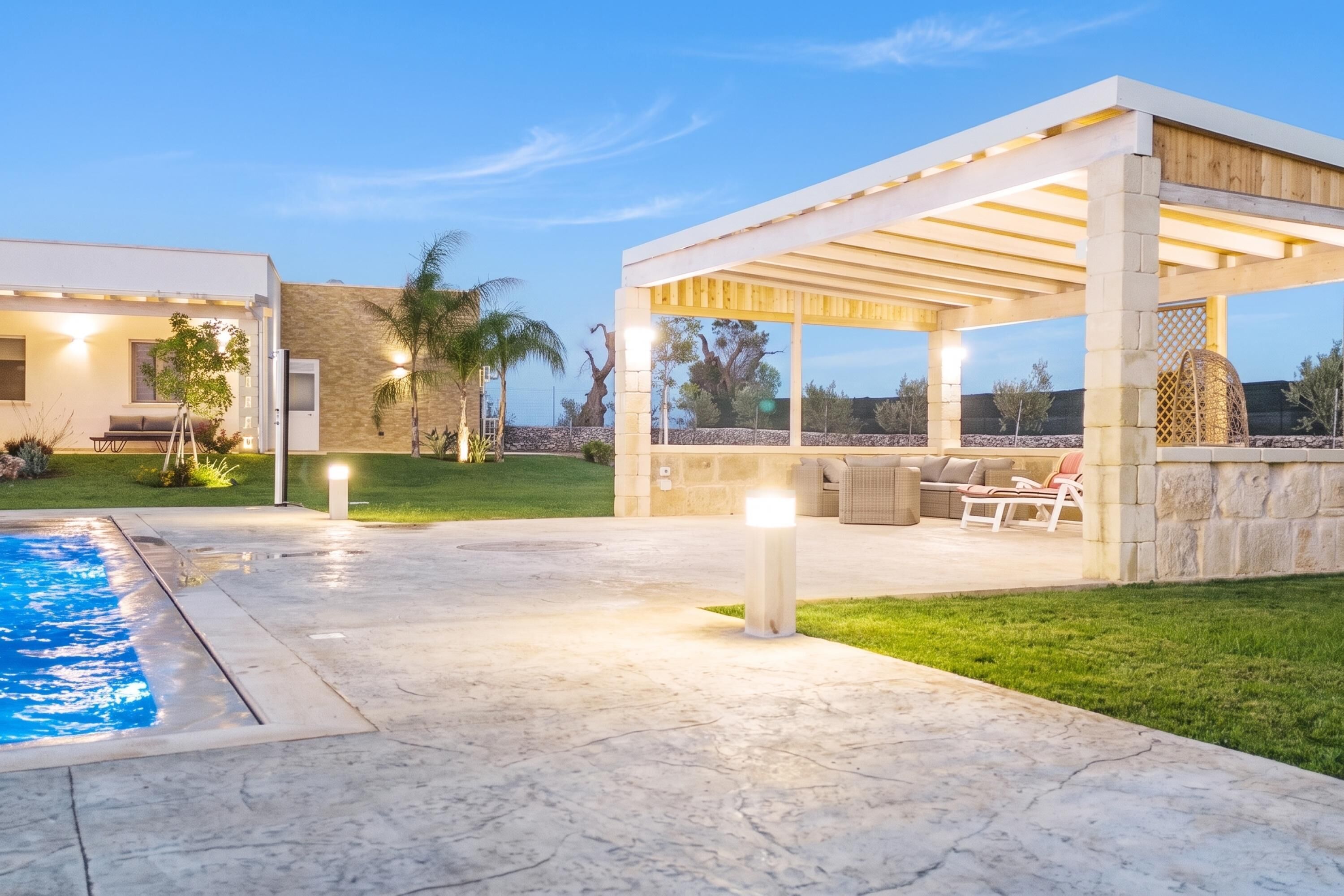 A modern outdoor patio area with a pool, seating, and a pergola.