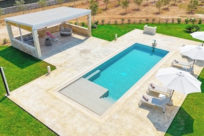 A rectangular swimming pool with a covered seating area and lounge chairs. - Tenuta Mary Relax & Pool (Carpignano Salentino)