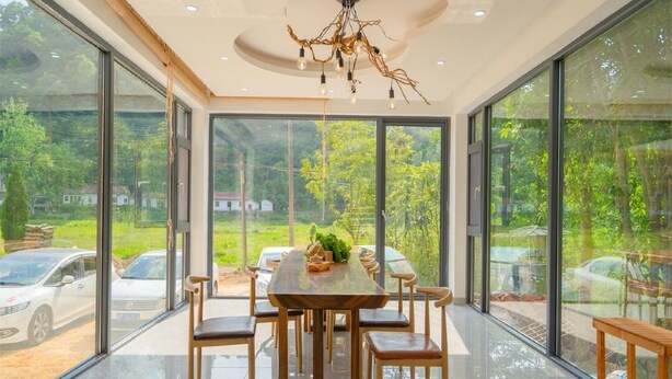 A dining area with a wooden table and chairs, large windows, and a unique chandelier. - gangwanriji (Xuancheng)
