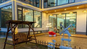 A modern building with large windows, a swing set, and a windmill sculpture. - gangwanriji (Xuancheng)