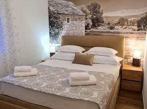 Une chambre à coucher avec un lit, des oreillers, une table de chevet et une fresque murale.