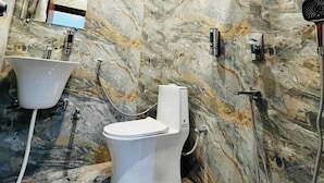 Une salle de bain avec un mur en marbre, une baignoire, des toilettes et une douche.