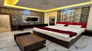 Une chambre à coucher moderne avec un grand lit, un téléviseur fixé au mur et une table de chevet en bois.