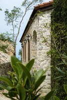 A stone building with a tiled roof and two black lantern-style lights.