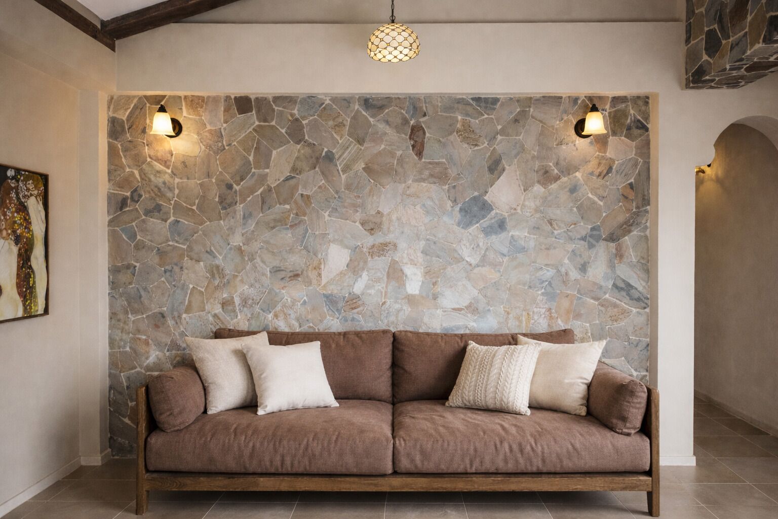 A room with a stone wall, a brown sofa, and two wall-mounted lights.