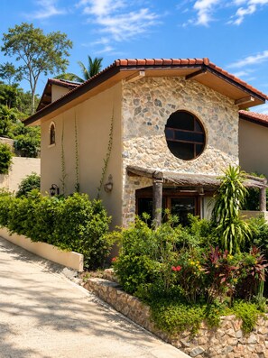 A house with a stone facade, a circular window, and a sloped roof. - eterna village (Ko Pha-ngan)