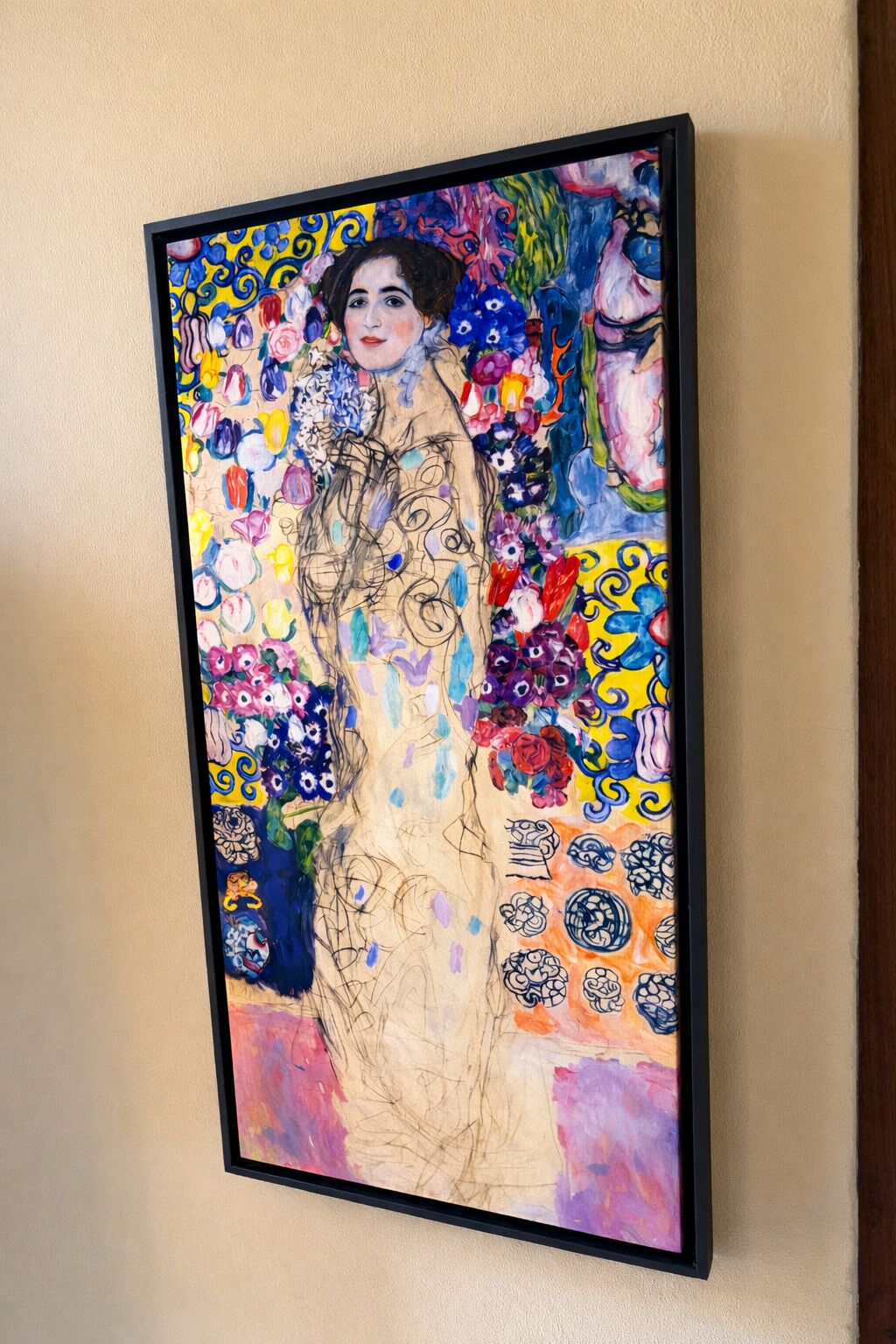 Un quadro incorniciato con una figura centrale circondata da motivi floreali colorati.